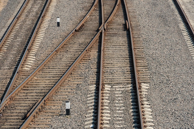 Вид на железную дорогу сверху Новая современная железная дорога с бетонными сваями и щебнем Пересечение железнодорожных путей на одном уровне Три ряда железнодорожных путей