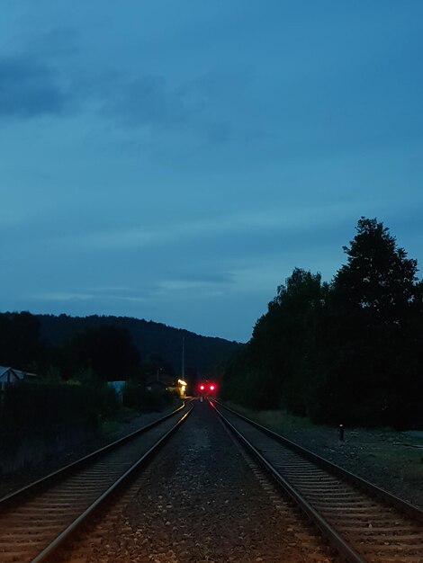 View of railway tracks against trees and sky