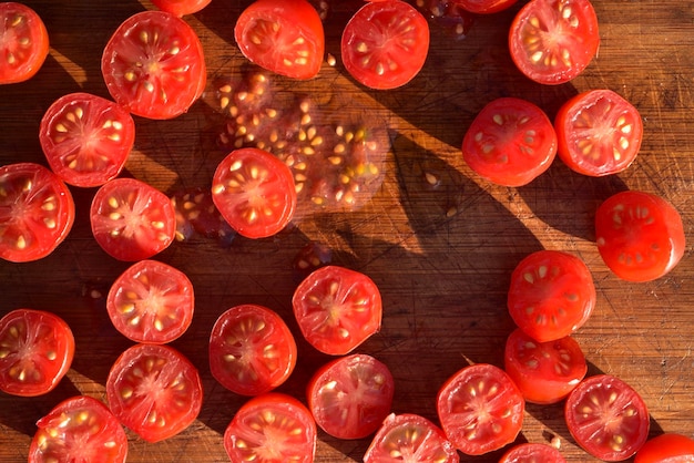Foto vista in alto di pomodori rossi tagliati a metà su un tavolo da taglio del legno