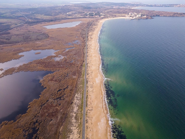 View of the road along the sea sandy coast from the drone cars drive on the road along the sea