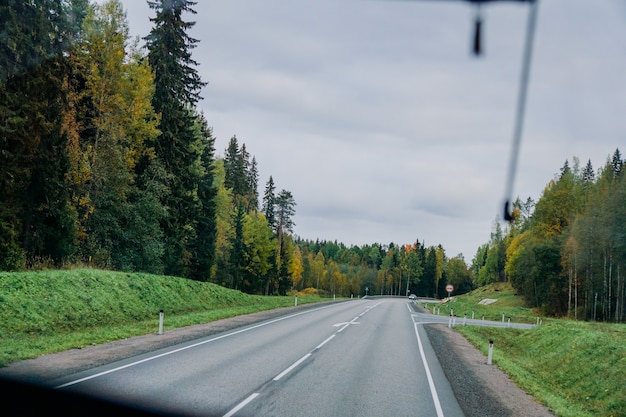 View of the road and the autumn forest through the bus window road trip