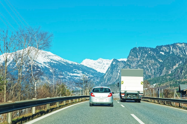 View of road with car and truck in winter Switzerland. Switzerland is a country in Europe. Switzerland has a high mountain range, from the Alps to Jura mountains.