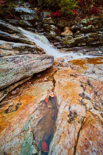 View of rocks in riverbed with puddle of water and waterfall in background