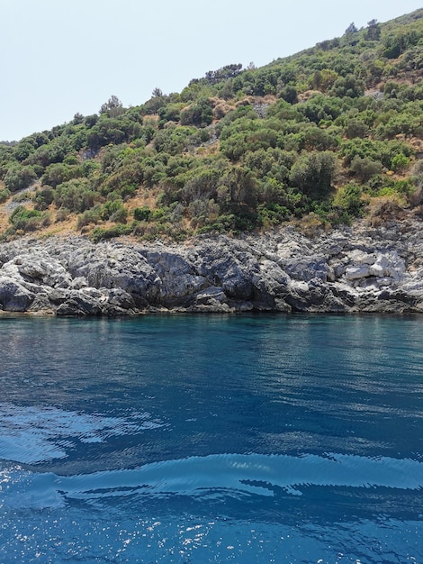 View of the rocky coast of the blue Aegean Sea from the water. Turkey, Kusadasi