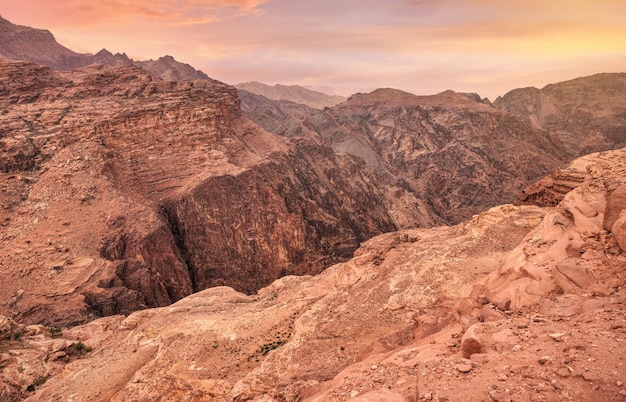 View to rocky landscape with orange pink clouds above from viewpoint near Ad Deir The Monastery in Petra Jordan