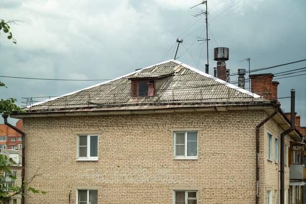 Вид на крышу старого кирпичного дома с дымоходами и множеством телевизионных антенн