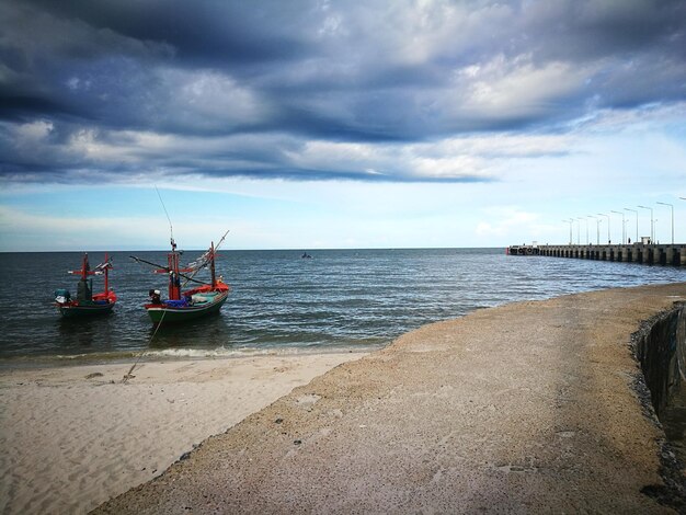 View of sailboat in sea against cloudy sky