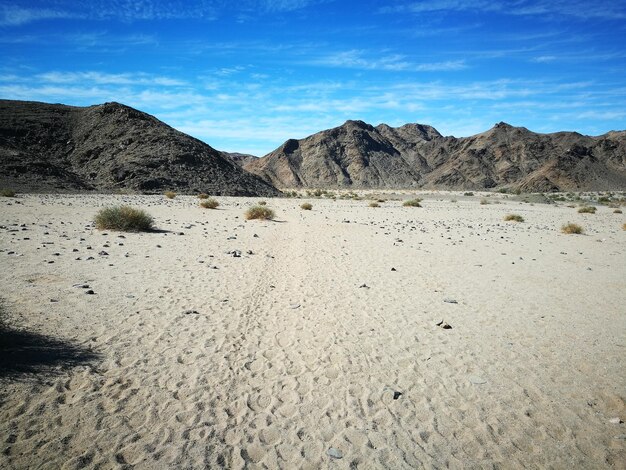 View of sandy field against mountains on sunny day