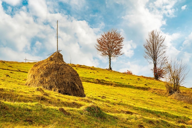 View of scenic landscape with bright colorful sky over foggy mountains. Majestic sunrise in misty morning valley with haystack on grassland hill. Concept of nature.