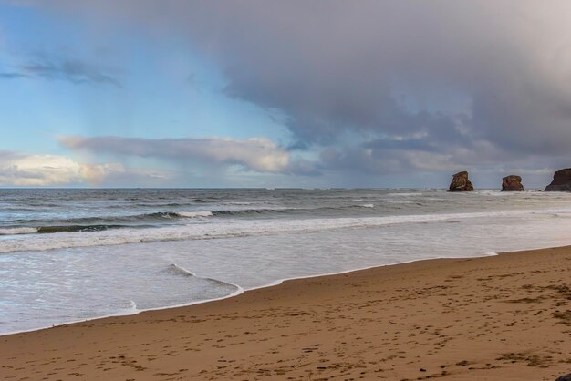 View of the sea waves breaking with white foam on the shore of hendaye beach france in the backg