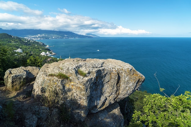 View of the sea and Yalta from the sunny path and an overhanging large stone . Crimea.