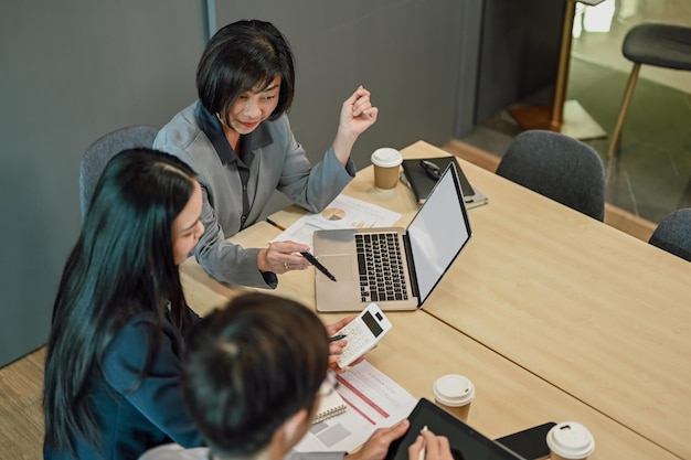 Above view of senior businesswoman in formal suit explaining strategy to her colleagues during meeting