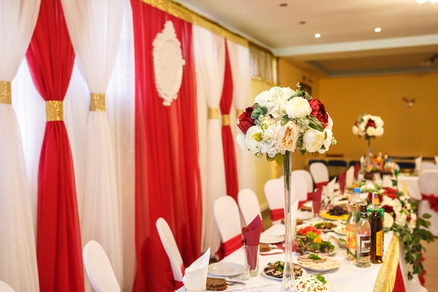 View of the served for decorated wedding dinner table in elite restaurant with beautiful flowers