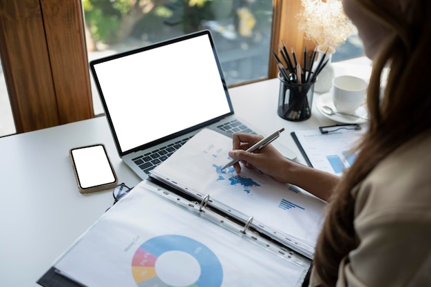 View over shoulder businesswoman checking financial graph and working with laptop