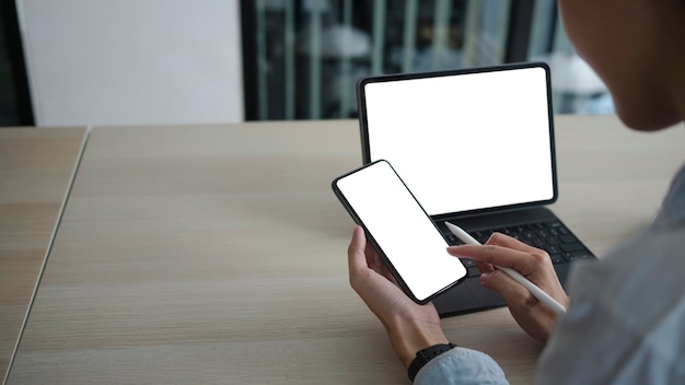 View over shoulder of businesswoman using mobile phone and working with computer tablet.