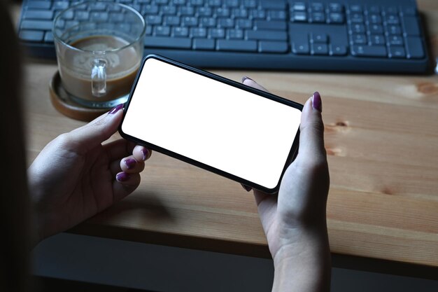 Photo view over shoulder woman holding smart phone with blank screen horizontally for watching video