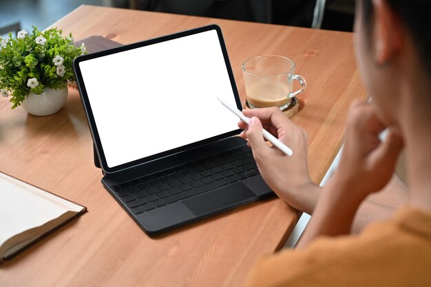 View over shoulder young man using computer tablet on wooden desk