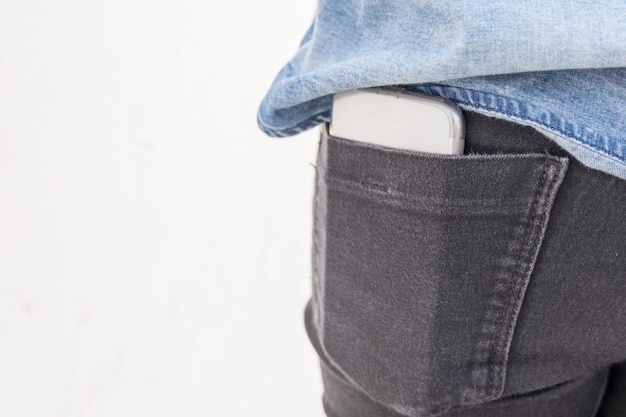 Foto vista di smartphone nella tasca dei jeans su uno sfondo bianco