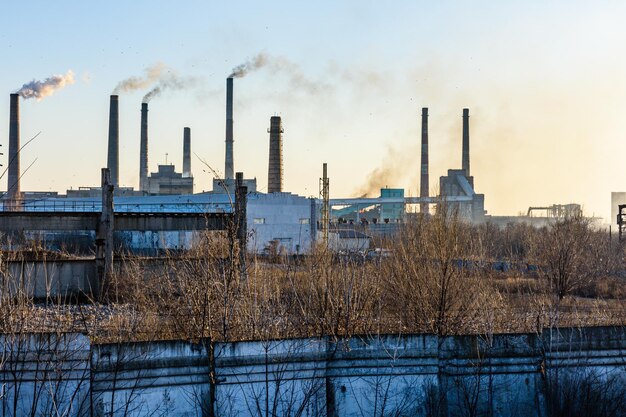 View on smoke pipes of the factory at sunset