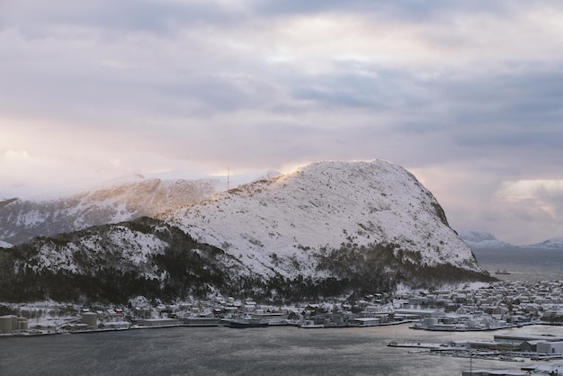 View of the snow covered mountain Sukkertoppen near the town of Alesund in Norway in winter