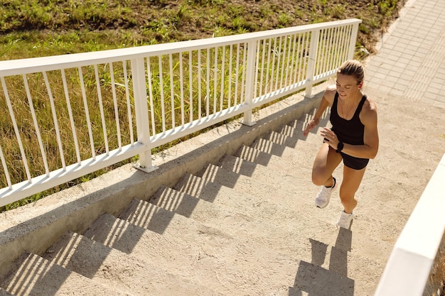Above view of sportswoman running up the stairs outdoors