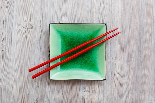 Above view square saucer with chopsticks on gray