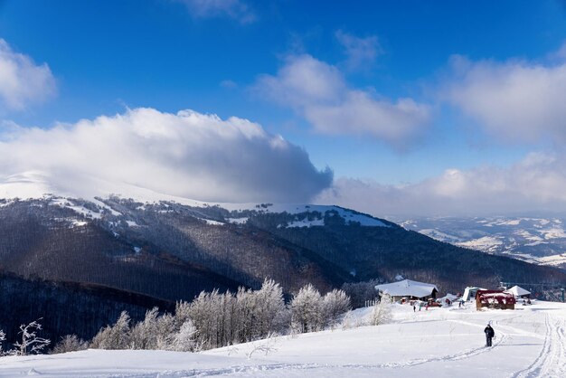 View of the stunning winter panorama of the snowy slopes and hills among the lush white clouds. The concept of bewitching harsh winter nature