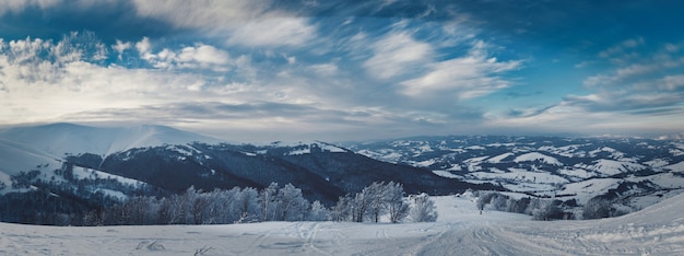 View of the stunning winter panorama of the snowy slopes and hills among the lush white clouds