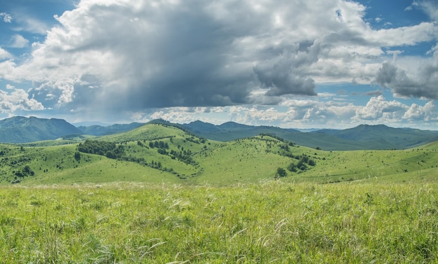 山の緑の牧草地の山の斜面と丘の夏の日のビュー