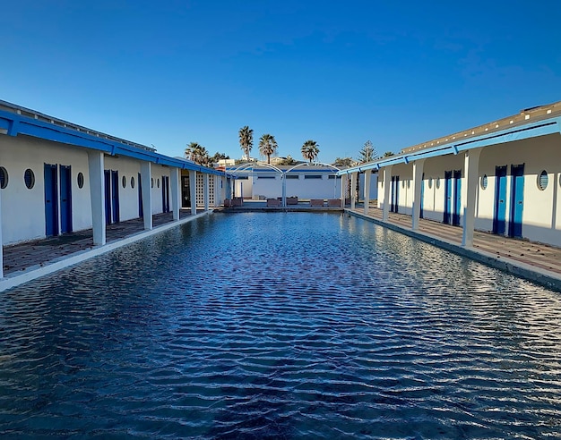 View of swimming pool by building against clear blue sky