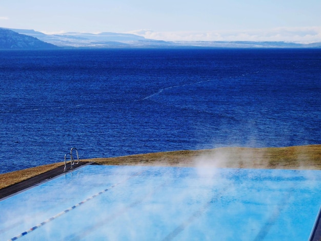 View of swimming pool by sea against sky