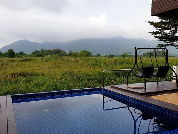 View of swimming pool with grass field and mountain