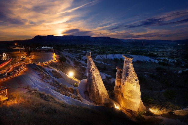 Vista dei camini delle fate, simbolo della cappadocia, illuminati da lanterne al tramonto