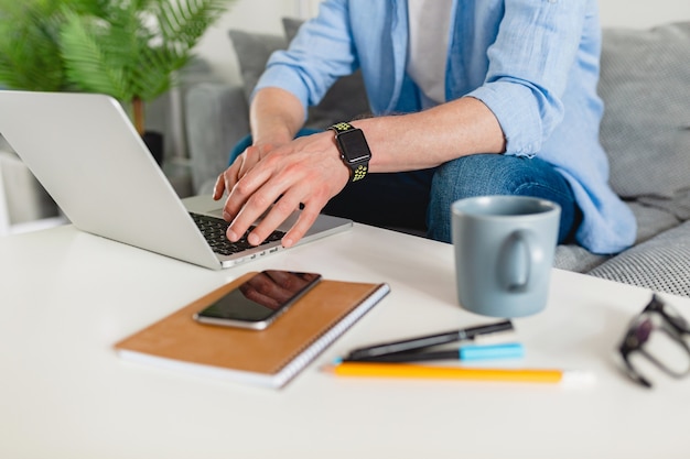 View on table workplace close-up man hands at home working typing on laptop