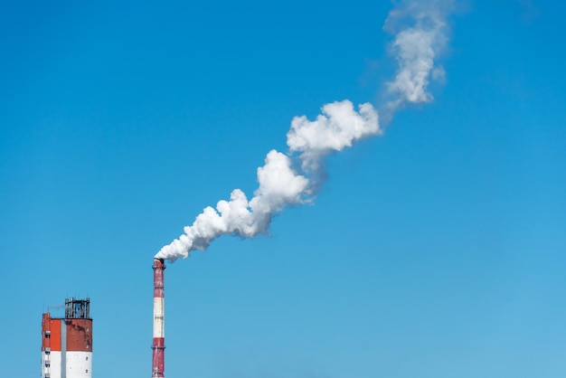 View of a thermal power plant or a factory for the production and processing of petroleum products Large industrial chimneys against a clear blue sky Removal of combustion