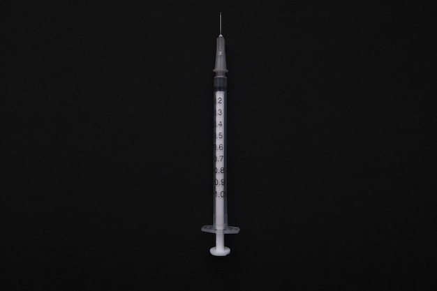 View of a thin syringe on black background