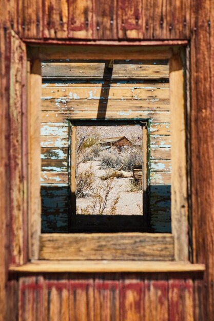 View through abandoned ghost town train with desert structure\
in window