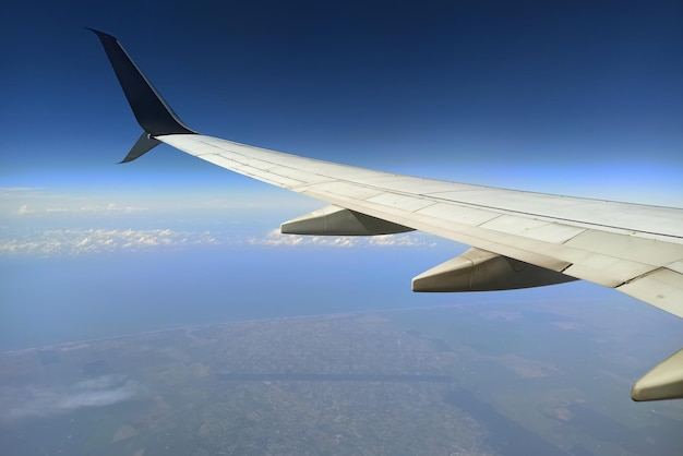 View through airplane window of commercial jet plane wing flying high in the sky Air travelling concept