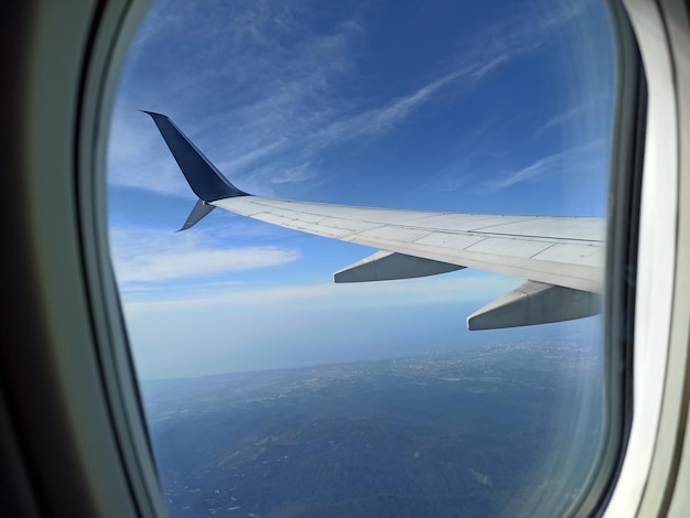 View through airplane window of commercial jet plane wing flying high in the sky Air travelling concept