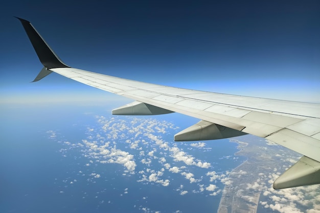 View through airplane window of commercial jet plane wing flying high in the sky Air travelling concept