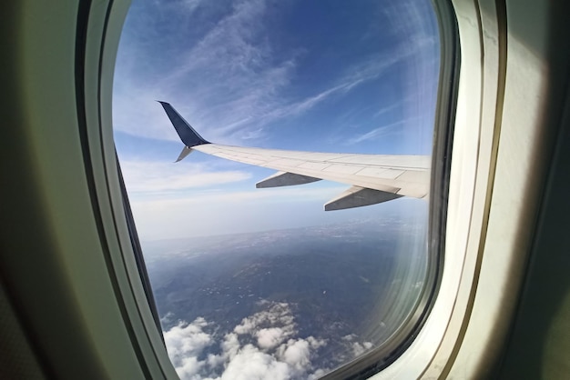 View through airplane window of commercial jet plane wing flying high in the sky Air travelling concept