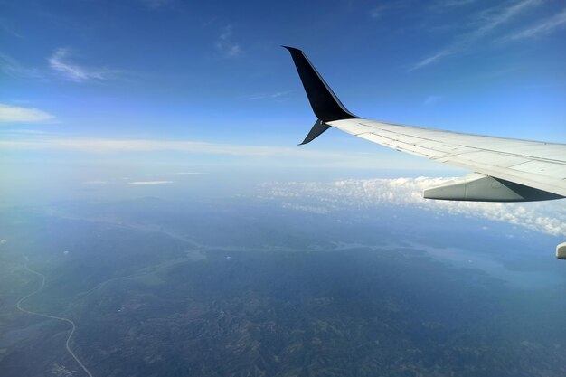 写真 空高く飛んでいる商用ジェット機の翼の飛行機の窓から見る空の旅のコンセプト