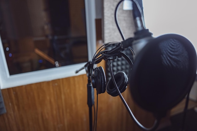 View through professional microphone and headphones to window with soundproof room in broadcasting and recording studio