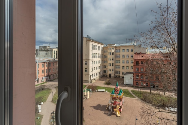 어린이 놀이터가 있는 상트페테르부르크의 안뜰 창을 통해 보기