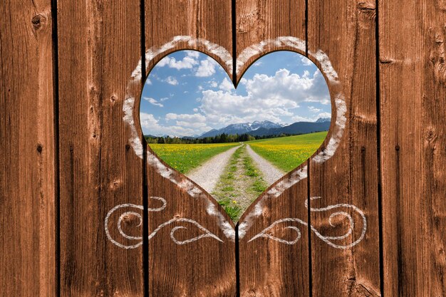 Photo view through wooden heart shape to single lane road in field