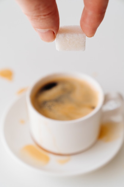 Visualizza in alto. tazza di caffè con latte e cubi di zucchero in mano. colazione mattutina tradizionale. vivacità nelle prime ascensioni mattutine. cappuccino