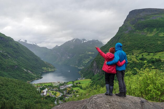 View of the tourist village Geiranger Norway Tourists stand at a panoramic point and look at Geirangerfjord and the mountains