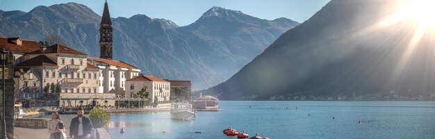View of town perast, montenegro and bay of kotor. scenic\
panorama view of historic town perast at famous bay of kotor with\
blooming flowers on beautiful sunny day with blue sky in summer,\
montenegro