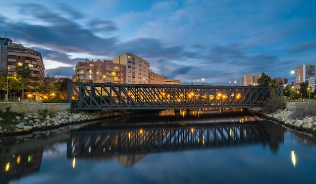 View of train bridge over Guadalmedina river in Malaga port at night.