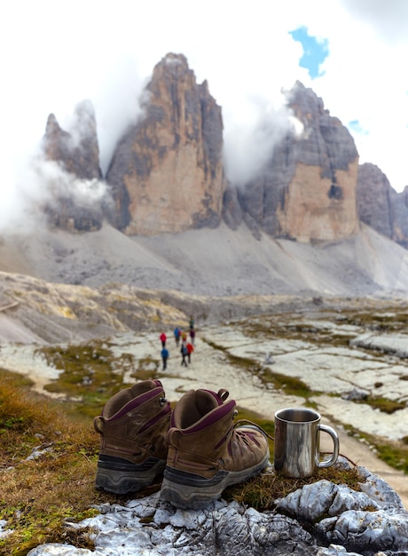 Вид на Тре Чиме ди Лаваредо с ботинками и чашкой на переднем плане. Доломиты, Италия.